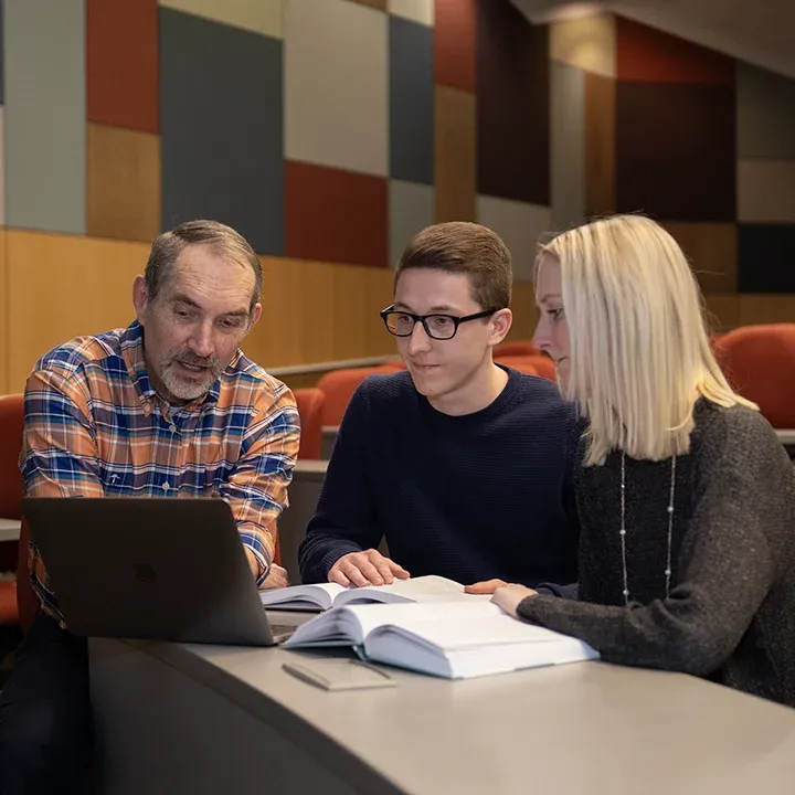 Students studying a text with a professor.