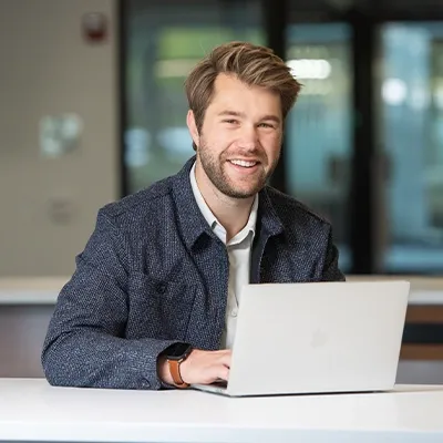 研究生 college 学生 smiling while working on laptop computer